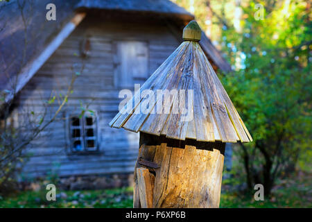 Un antico alveare in legno per le api con un tetto di base in autunno foresta accanto a un vintage house nel Museo Etnografico della Lettonia Foto Stock