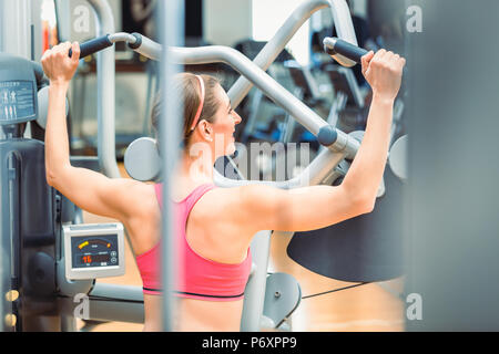 Vista posteriore di una donna fit con bracci tonico e torna per gli esercizi in palestra Foto Stock