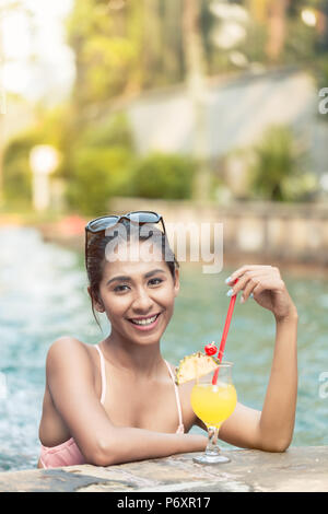 Ritratto di una bella donna asiatica di bere un cocktail di ananas in piscina Foto Stock