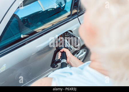 Close-up della mano di una donna senior il riempimento del serbatoio di gas della sua automobile Foto Stock