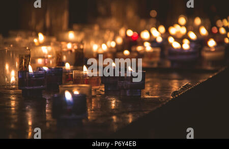 Piccole candele nel buio in una chiesa in Francia Foto Stock