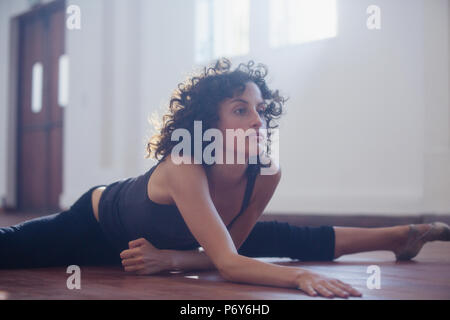 Forte giovane ballerino femmina stretching in studio di danza Foto Stock