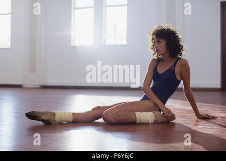 Forte giovane ballerino femmina allungamento della gamba in studio di danza Foto Stock