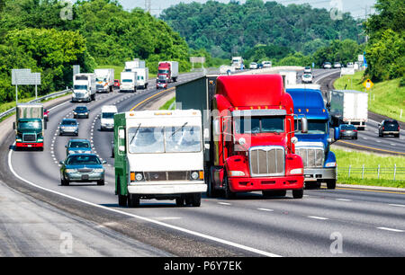 Colori americani riflettono in tre camion che portano il traffico su un'autostrada. Girato in giornata calda. Asfalto ondate di calore causa la deformazione su veicoli lontano Foto Stock