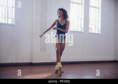 Sorridente giovane ballerino femmina la pratica in studio di danza Foto Stock