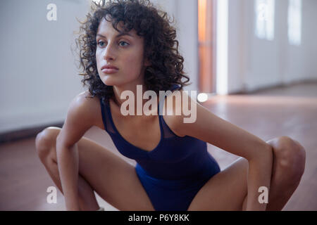 Concentrati, forte giovane ballerino femmina stretching in studio di danza Foto Stock