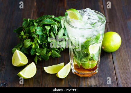 I Mojito erano sporchi e gli ingredienti (menta fresca, fettine di lime) servita al buio su un pannello di legno. Risoluzione alta. Foto Stock
