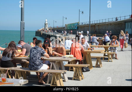 Per coloro che godono di un drink al sole, al waterside tabelle, sul lungomare porto il braccio a Folkestone Harbour, Kent, Regno Unito Foto Stock