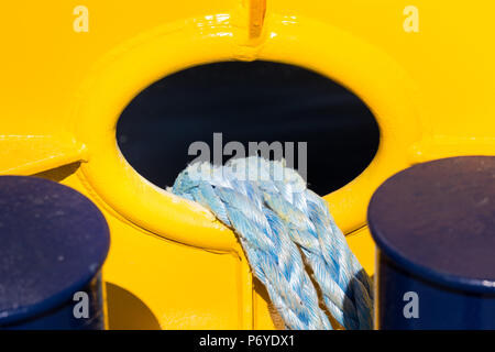 Due funi azzurrognolo appeso nel foro ovale del giallo muro di ferro Foto Stock