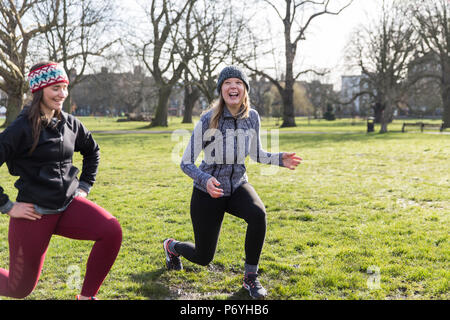 Sorridente, fiduciosi le donne facendo balzi in avanti nel soleggiato parco Foto Stock