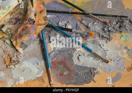 I pennelli e uno straccio giacente su un bordo con colori misti. concetto: artistica e creativa caos Foto Stock