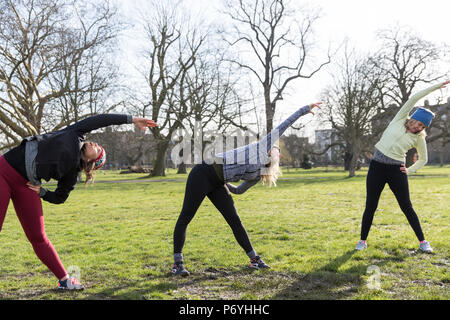 Runner donna stretching nel soleggiato parco Foto Stock