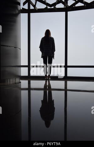 Un riflesso di una ragazza in piedi sul ponte di visualizzazione di Burj Khalifa. Foto Stock