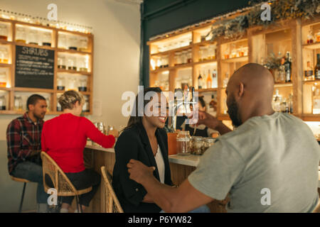 Sorridente americano africano giovane godendo bevande insieme in un bar Foto Stock