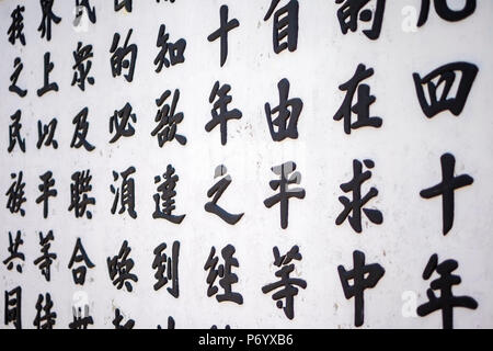 I caratteri cinesi dipinta su un muro bianco in un tempio buddista in Hoi An, Quang Nam Provincia, Vietnam Foto Stock