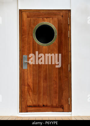 Porta in legno con oblò a bordo di una nave Foto Stock