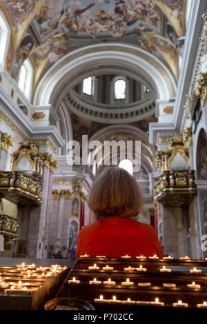 Una signora il visitatore alla Cattedrale di San Nicola si siede in un pew con il suo ritorno a candele accese, nella capitale slovena di Lubiana, il 28 giugno 2018, a Ljubljana, Slovenia. Foto Stock