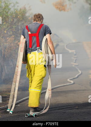 Melbourne, Australia - 13 Aprile 2018: Fire fighter con rotoli di tubo antincendio a una bussola incendio in un'area suburbana di Knox City a est di Melbourne. Foto Stock