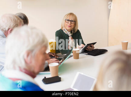 Ritratto fiducioso senior imprenditrice con tavoletta digitale che conduce alla sala conferenze Sale riunioni Foto Stock