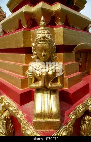 Un Buddha d'oro inginocchiato in preghiera in un angolo del tempio Foto Stock