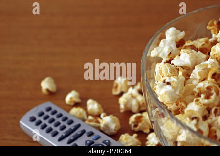 Il Popcorn in una ciotola accanto a un telecomando Foto Stock