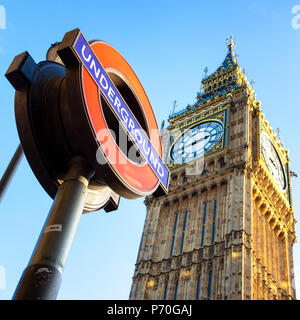 London, Regno Unito - 20 Novembre 2013: le case del Parlamento di clock tower, Big Ben, con la metropolitana di Londra sign in primo piano, contro il cielo blu bac Foto Stock