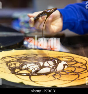 Venditore ambulante prepara il cioccolato tradizionale e banana crepes ad una strada del mercato di Berlino. Foto Stock