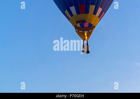 Il fondo di un palloncino volare (aerostato), con aeronauts in un cesto e un fuoco ardente, contro un cielo blu Foto Stock