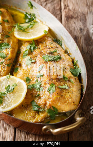 In casa filetto di trota ricetta con burro all'aglio, salsa di limone e prezzemolo close-up in rame in padella sul piano verticale. Foto Stock