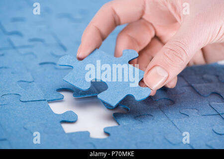 Immagine ritagliata di imprenditrice inserimento ultimo puzzle mancante, la concezione di business Foto Stock