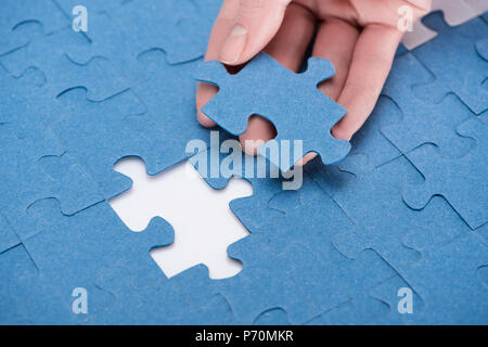 Immagine ritagliata di imprenditrice inserimento ultimo puzzle mancante, la concezione di business Foto Stock