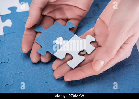 Immagine ritagliata di imprenditrice assemblaggio di blu e bianco puzzle insieme, la concezione di business Foto Stock