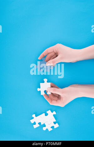 Immagine ritagliata di imprenditrice assemblaggio di blu e bianco puzzle isolato sul blu, la concezione di business Foto Stock