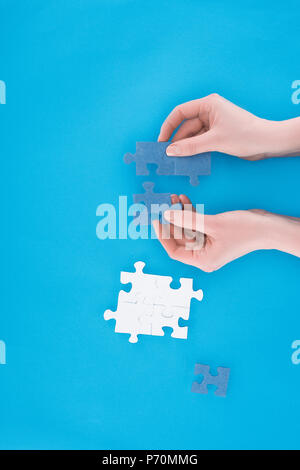 Immagine ritagliata di imprenditrice assemblaggio puzzle blu isolato sul blu, la concezione di business Foto Stock