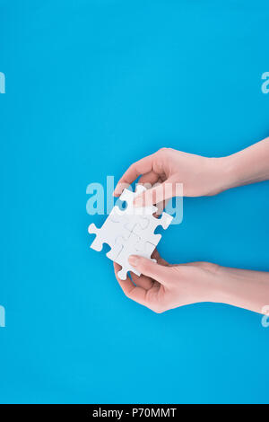 Immagine ritagliata di imprenditrice azienda assemblati puzzle isolato sul blu, la concezione di business Foto Stock