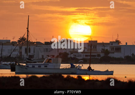 Barca tradizionale, llaüt, e altre imbarcazioni in Estany des Peix marine laguna con il sorgere del sole nel Parco Naturale di Ses Salines (Formentera, isole Baleari) Foto Stock