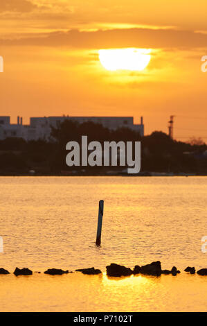 Sunrise a Estany des Peix marine laguna con La Savina edifici in background nel Parco Naturale di Ses Salines (Formentera, isole Baleari, Spagna) Foto Stock