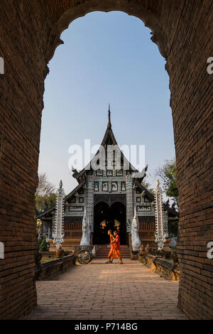 Tempio Wat Lok Moli visto attraverso un arco con due monaci a piedi da, Chiang Mai, Thailandia, Sud-est asiatico, in Asia Foto Stock