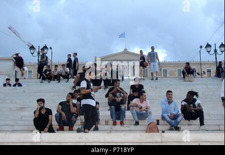 Un gruppo di giovani uomini siedono sui gradini davanti al parlamento greco ad Atene in Grecia Foto Stock