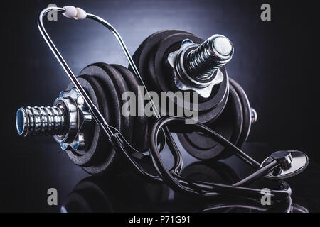 Vista ravvicinata di manubri e stetoscopio, uno stile di vita sano concetto Foto Stock