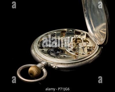 Il vecchio orologio da tasca nero a superficie riflettente, lato posteriore coperchio aperto e la precisione di un orologio visibile Foto Stock