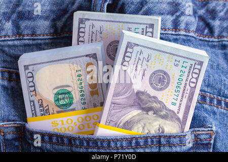 Jeans blu farcite con pile di denaro contante. Foto Stock