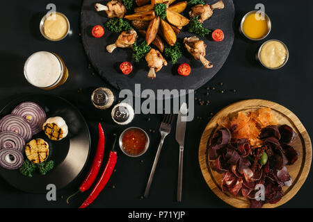 Delizioso assortimento di carne con patate al forno, salse e pollo arrosto su nero Foto Stock