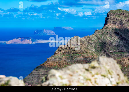 Lanzarote isole Canarie Spagna, elevati vista panorama dalla vetta del blu oceano Atlantico con espressivo molla luminoso cielo con nuvole bianche e tre piccole isole in background Foto Stock