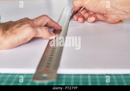 Marcatura le mani una lavagna, ruller e matita su un tappeto verde sullo sfondo Foto Stock