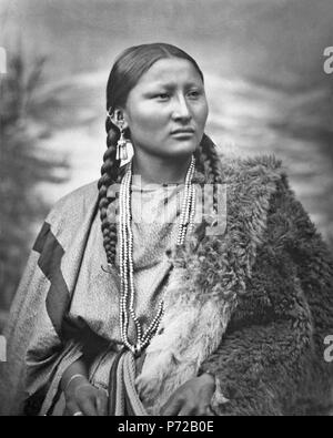 Cheyenne o Arapaho donna graziosa naso a Fort Keogh, Montana, Stati Uniti. Indossa abiti di stoffa con tessuto della cinghia e buffalo robe, così come orecchini, bracciali, anelli e collana. Collotipia. 1879 7 Arapaho donna graziosa naso, 1879, restaurato Foto Stock