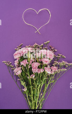 Bouquet di bellissimi fiori rosa e a forma di cuore sulla corda viola Foto Stock