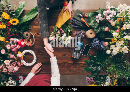 Immagine ritagliata del fioraio e il cliente si stringono la mano Foto Stock