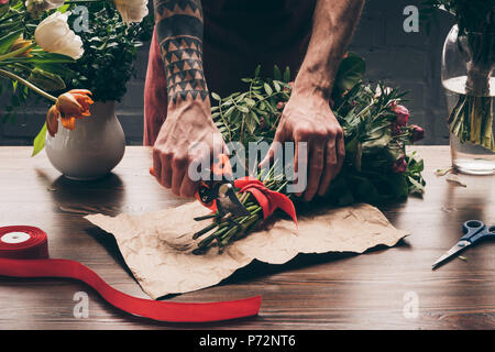 Immagine ritagliata del fioraio con tatuaggio sulla mano stocchi di taglio con sistema di eliminazione Foto Stock