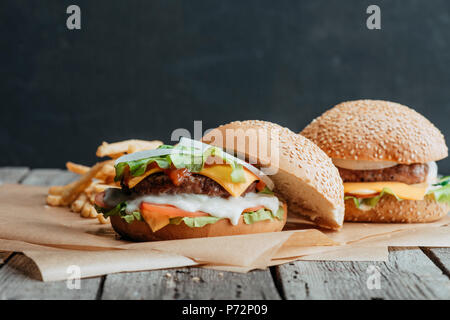 Gustosi piatti fatti in casa cheeseburger sulla carta da forno con patate fritte Foto Stock